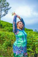 a tea garden farmer is posing beautifully in the middle of green tea leaves photo