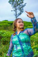 an Asian woman in a blue peasant dress standing among the tea gardens photo