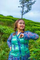 an Asian woman in a blue peasant dress standing among the tea gardens photo