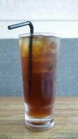 A tall glass of ice tea with a straw on the table. photo