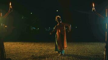 a traditional Asian dancer is dancing among the flames of torches that burn with yellow light video