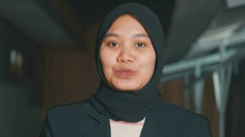 a muslim reporter in a headscarf and a black coat is talking in front of the camera with a smiling face video