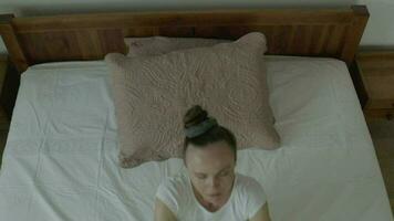 un mujer en blanco pantalones es tendido en un cama video