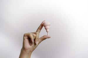 Close up of woman hand holding menstrual cup over white background. Women health concept, zero waste alternatives photo