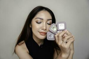 Indonesian beautiful female holding eyeshadow that she used on her eyes. Clean skin, fashion naturel make-up. Good vision photo