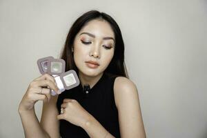 Indonesian beautiful female holding eyeshadow that she used on her eyes. Clean skin, fashion naturel make-up. Good vision photo