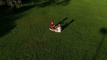 a girl and a boy holding a house cutout sitting in the grass on a