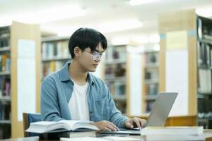 Young university student using laptop for online learning, searching and learning at library. photo