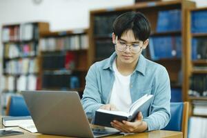 Young university student using laptop for online learning, searching and learning at library. photo