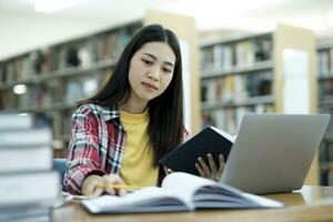 Young university student using laptop for online learning, searching and learning at library. photo