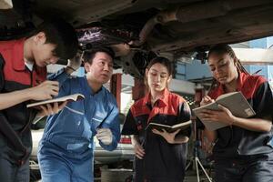 Specialist lecture, male supervisor engineer describe gasoline automotive fixing with mechanic worker staff teams for repair work at car service garage and maintenance jobs in automobile industry. photo