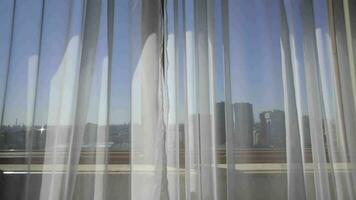 a window with sheer curtains and a city view video