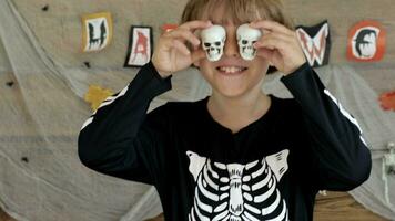 a boy wearing a halloween shirt and holding up two halloween skulls video