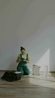 a woman in overalls is sitting on the floor fixing a chair video