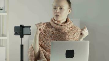 a woman sitting at a desk with a laptop doing live stream video