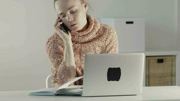 a woman is using a laptop while sitting at a table video