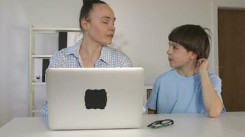 un mujer y un chico sentado a un escritorio con un ordenador portátil video