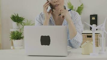 a woman in glasses talking on the phone while sitting at a desk video