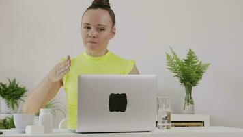 a woman is sitting at a desk with a laptop doing vlog or live stream video