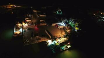 Aerial view of loading from fishing ships to cargo trucks in harbor port at night video