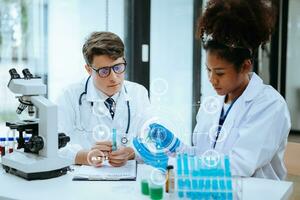 Focused mature male doctor and African female nurse look at tablet and laptop screen discuss anamnesis together. Concentrated diverse medical professionals photo