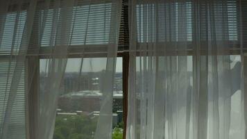 a window with white curtains and a view of the city video