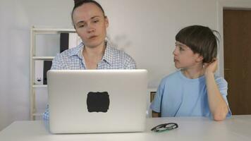 un mujer y un chico son mirando a un ordenador portátil video