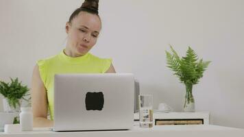 a woman is sitting at a desk with a laptop doing vlog or live stream video