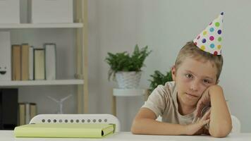 a boy wearing a party hat sits at a table video