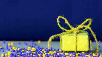 a small gift box with yellow and blue beads on a blue background video