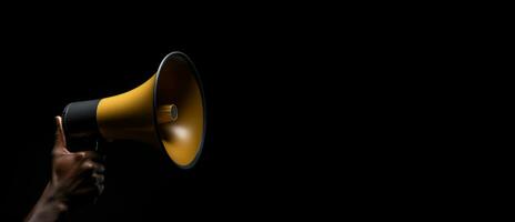 Generative AI, golden megaphone in hand on a empty black background, panoramic image with copy space photo