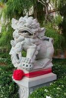 a stone lion statue with a red ribbon around it photo