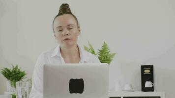 a woman is sitting at a desk with her laptop video