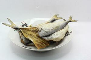 Deep-fried salted fish, 3 tail sections placed in a plate, on a white background, closeup of photo