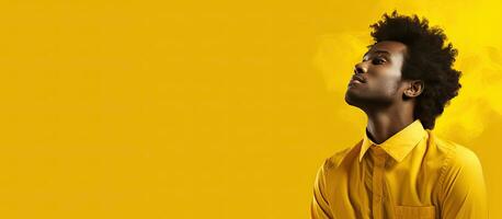 African man contemplating on yellow background with room for writing photo