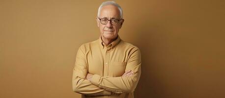 Waist up portrait of elderly man in glasses arms crossed looking at camera against beige background photo