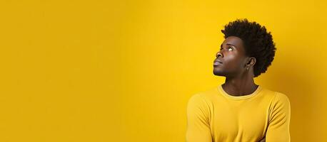 African man contemplating on yellow background with room for writing photo