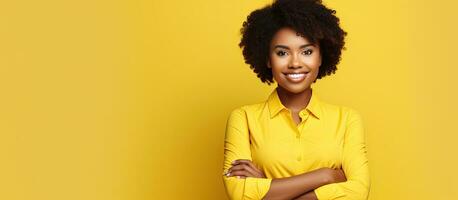 joven africano americano mujer con confidente y sonriente comportamiento posando en amarillo antecedentes cruce brazos en cofre y mantener ojo contacto con California foto