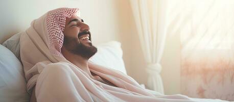 un árabe hombre bien descansado despertar arriba sonriente y disfrutando un agradable Mañana en cama foto