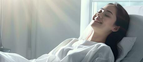 Woman lying on bed in clinic wearing patient gown with a positive attitude photo