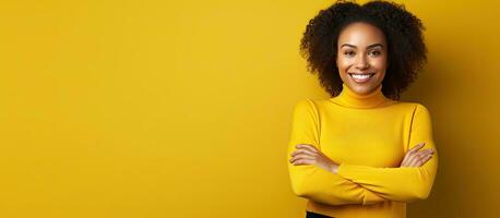 joven africano americano mujer con confidente y sonriente comportamiento posando en amarillo antecedentes cruce brazos en cofre y mantener ojo contacto con California foto