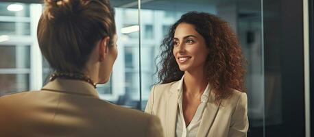 Successful modern businesswoman having a conversation with partner and using laptop in office standing by window photo