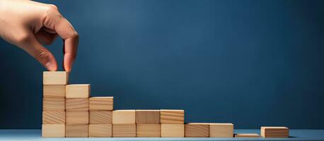A woman aligns wooden blocks to create a step like structure on a blue background representing the growth and success of a business concept photo
