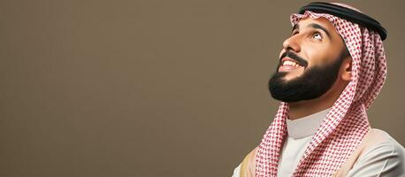 Thoughtful young Arab man daydreaming and looking up against a blank wall photo