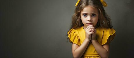 Unhappy young girl in yellow dress hands by face against gray backdrop photo