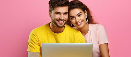 A couple working on a laptop hugging isolated on a yellow wall background photo