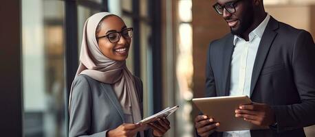 African American man and Muslim businesswoman in office holding documents walking towards camera photo