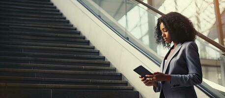 A black businesswoman using digital tablet while descending stairs at the office Empty area photo