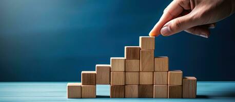 A woman aligns wooden blocks to create a step like structure on a blue background representing the growth and success of a business concept photo