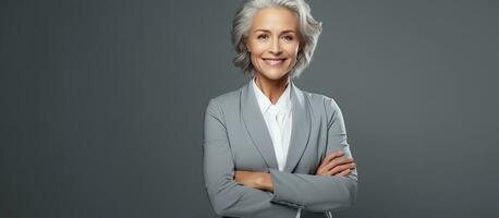 High quality photo of a mature businesswoman in a suit smiling and looking at empty space on a gray background